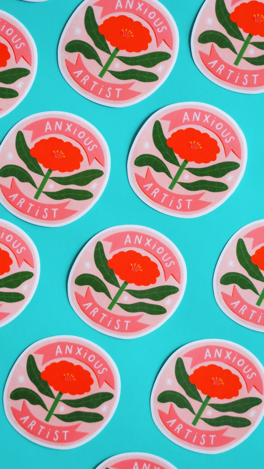 round vinyl sticker with a big red flower on it, the text reads 'anxious artist' background is pink and leaves are green