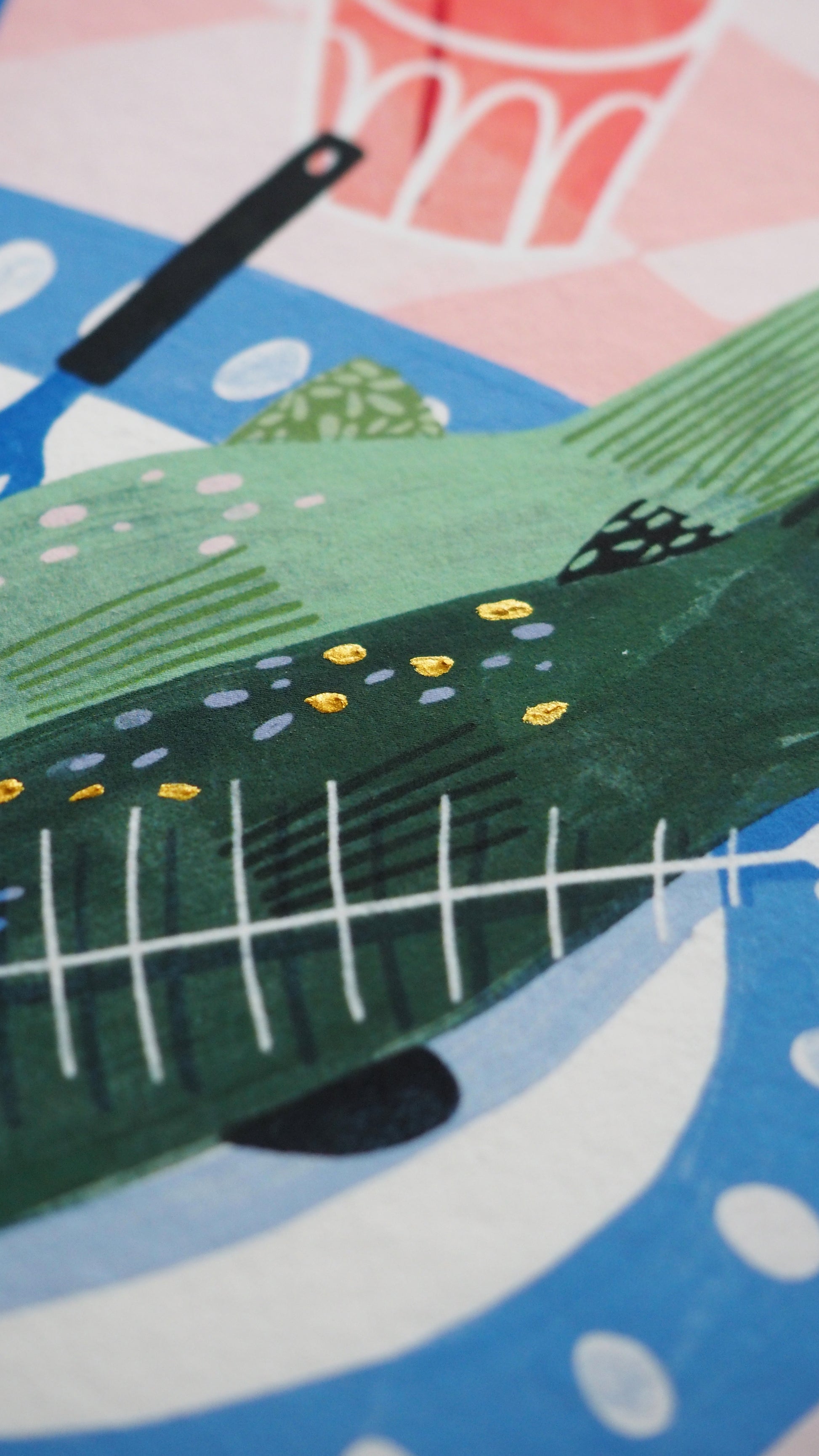 limited edition print, of a Mediterranean table, a plate of fish, bowl of olives, some oranges a candle and a bottle of olive oil on a gingham tablecloth. Green blue and terracotta colours. close up of the details on the print. finished with gold paint