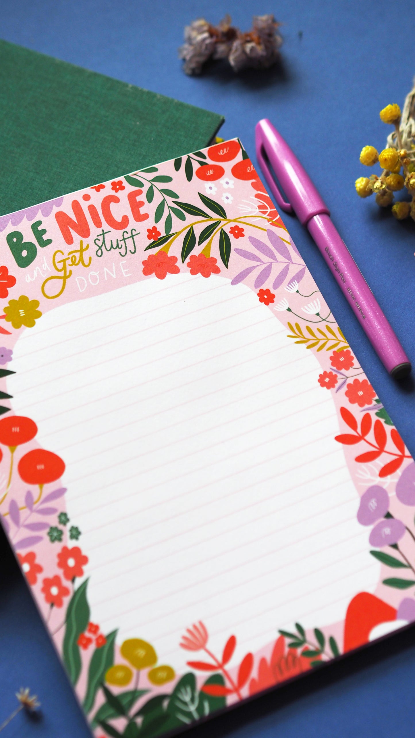 A5 list pad with 'be nice and get stuff done' written at the top in illustrated type, a floral border around the edge of the lined section with lots of fun florals and leaves. pink, green red and lilac are the main colours