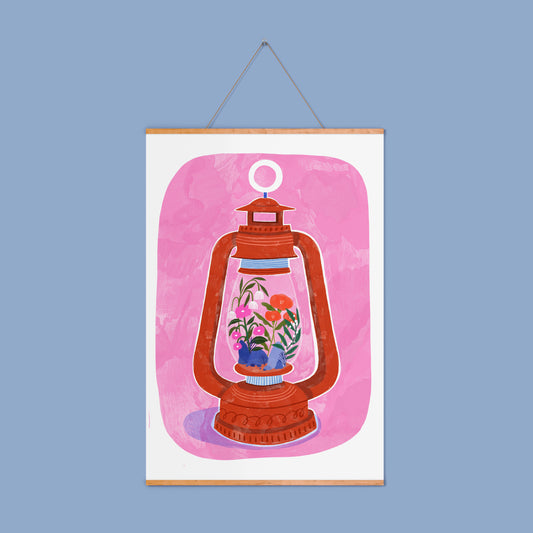 pink background with a terracotta lantern on, within the glass of the lantern there are lots of small flowers and rocks, that look like a garden! 